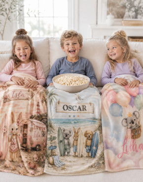 Three children cuddled under personalised fleece blankets in a cosy neutral living room