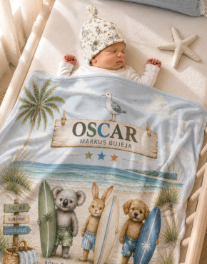 Personalised baby blanket and matching beanie set with coastal animal design, featuring a sleeping newborn wrapped in a soft blue beach-themed blanket with name Oscar printed, styled in a neutral nursery cot setting.